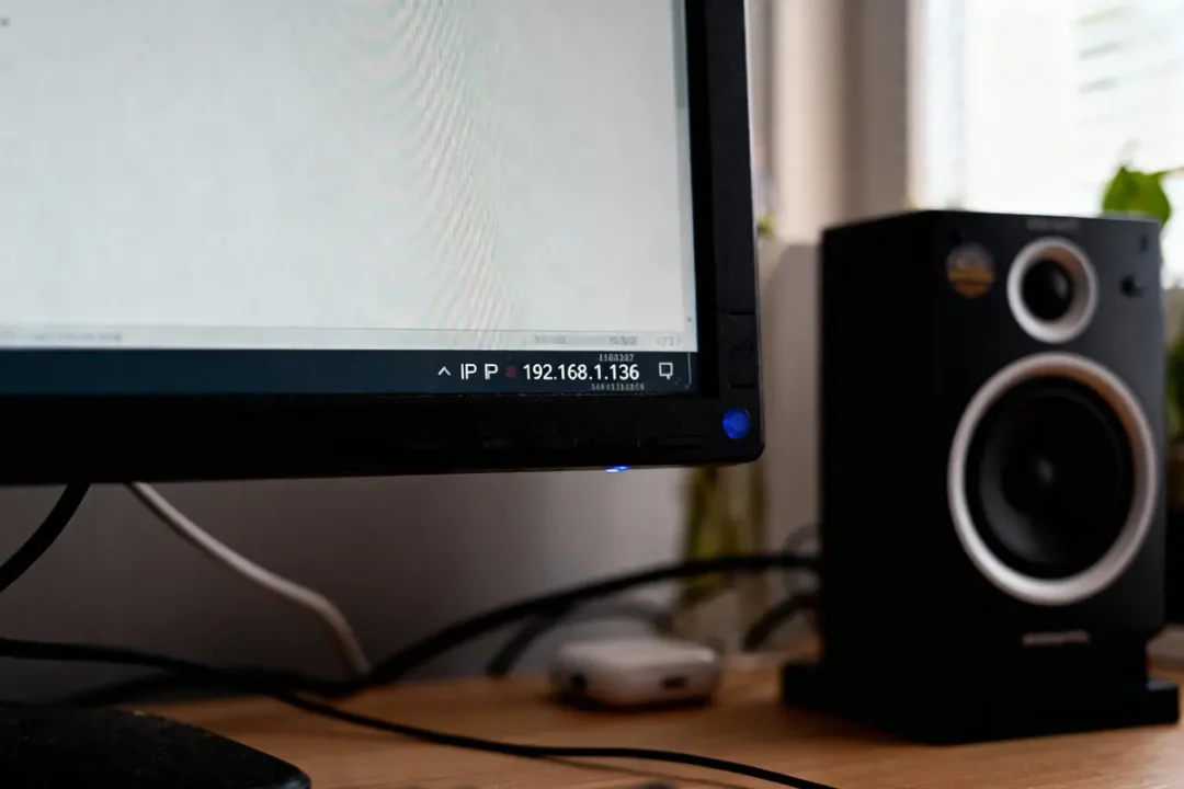 Écran avec adresse IP affichée, enceintes noires, câbles connectés sur un bureau en bois.