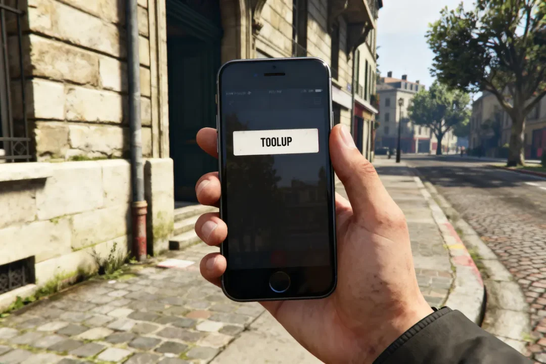 Main tenant smartphone affichant "TOOLUP", rue pavée et bâtiments en arrière-plan.