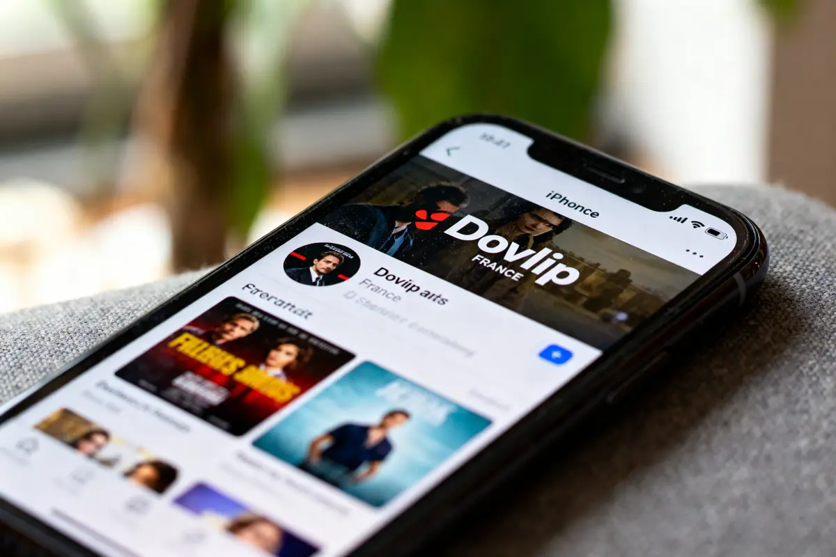 Smartphone affichant la page d'un profil sur une application de réseaux sociaux, avec plusieurs images et textes visibles.