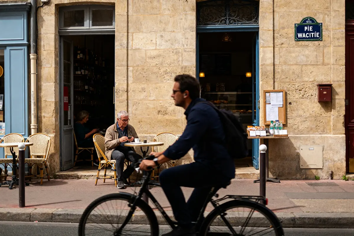Cycliste passe devant café animé cherchant wawacity nouvelle adresse pour découvrir nouveautés Internet