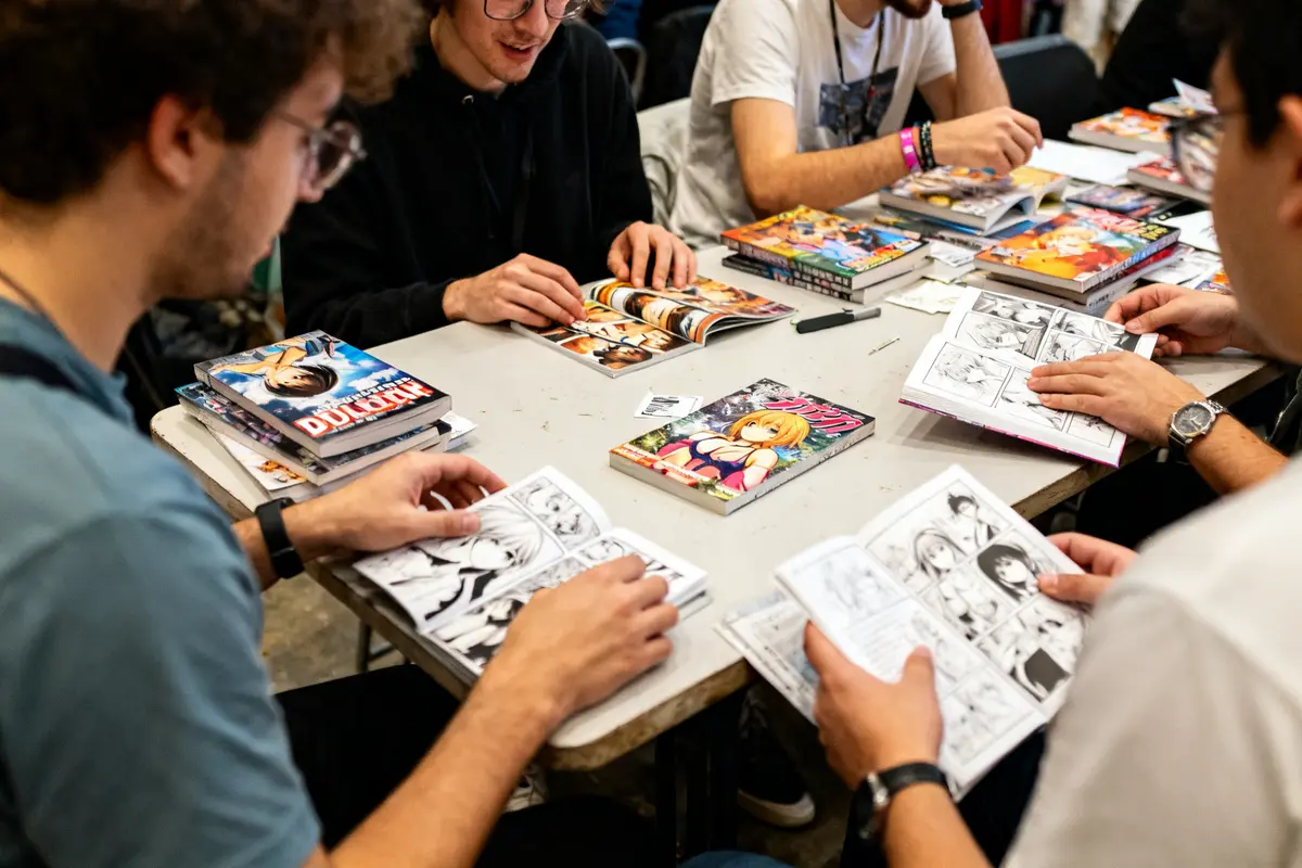 Des personnes lisant des mangas et doujin fr autour d'une table lors d'un événement