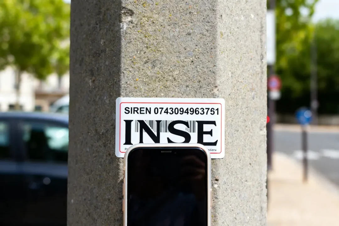 Plaque SIREN sur poteau illustrant immatriculation insee c'est quoi avec téléphone en arrière-plan