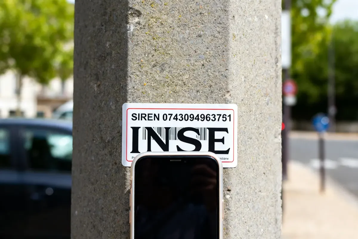 Plaque SIREN sur poteau illustrant immatriculation insee c'est quoi avec téléphone en arrière-plan