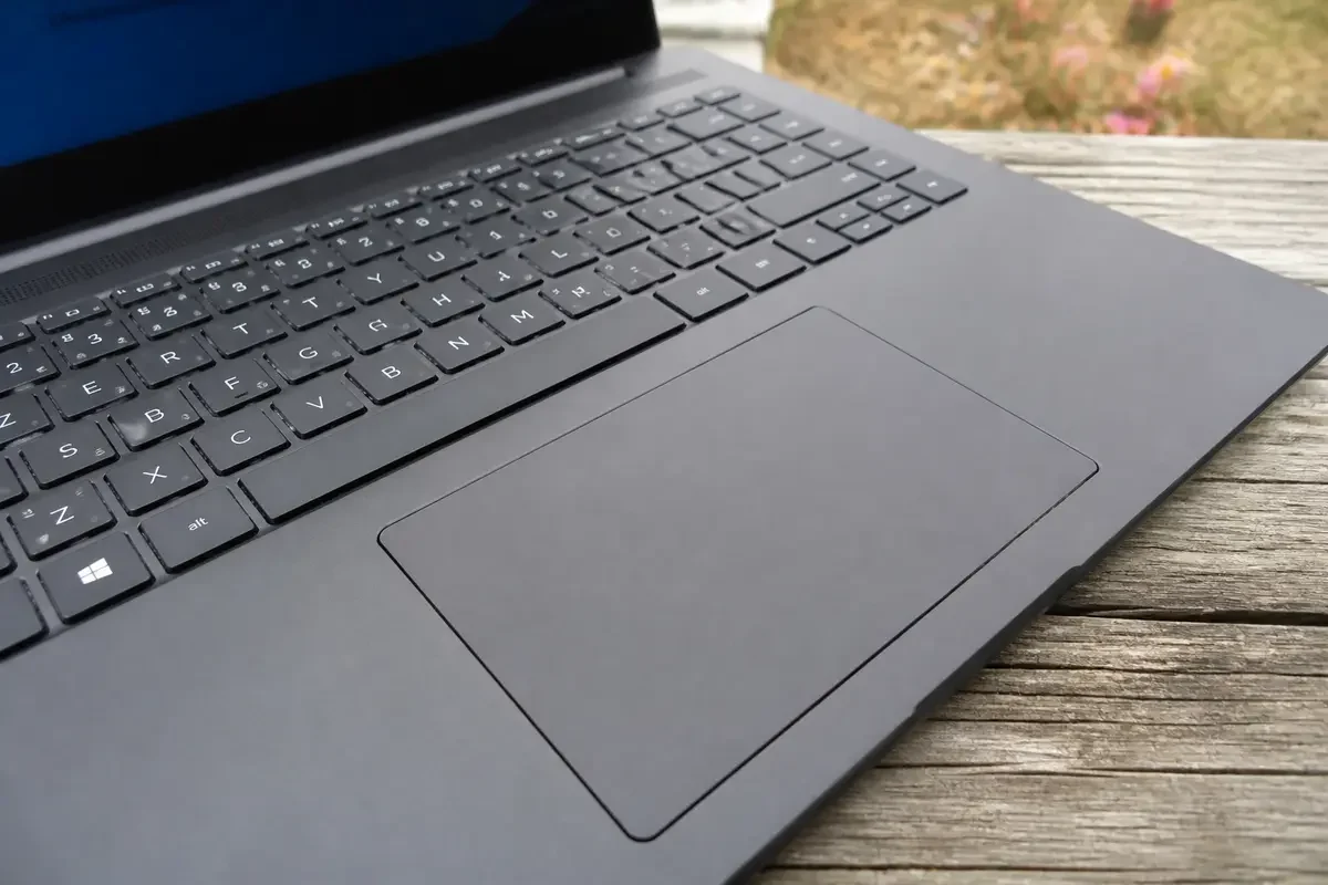 Clavier sur ordinateur portable noir posé sur une table en bois à l'extérieur