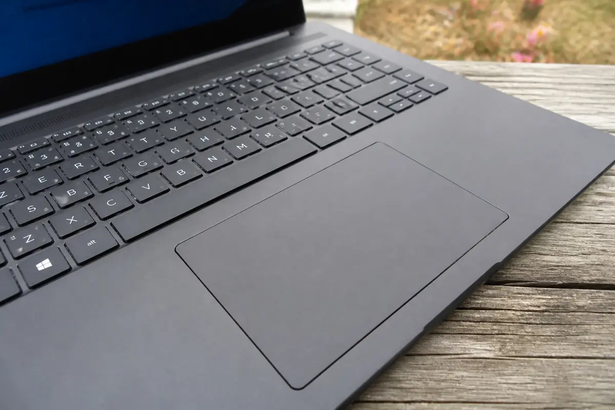 Clavier sur ordinateur portable noir posé sur une table en bois à l'extérieur